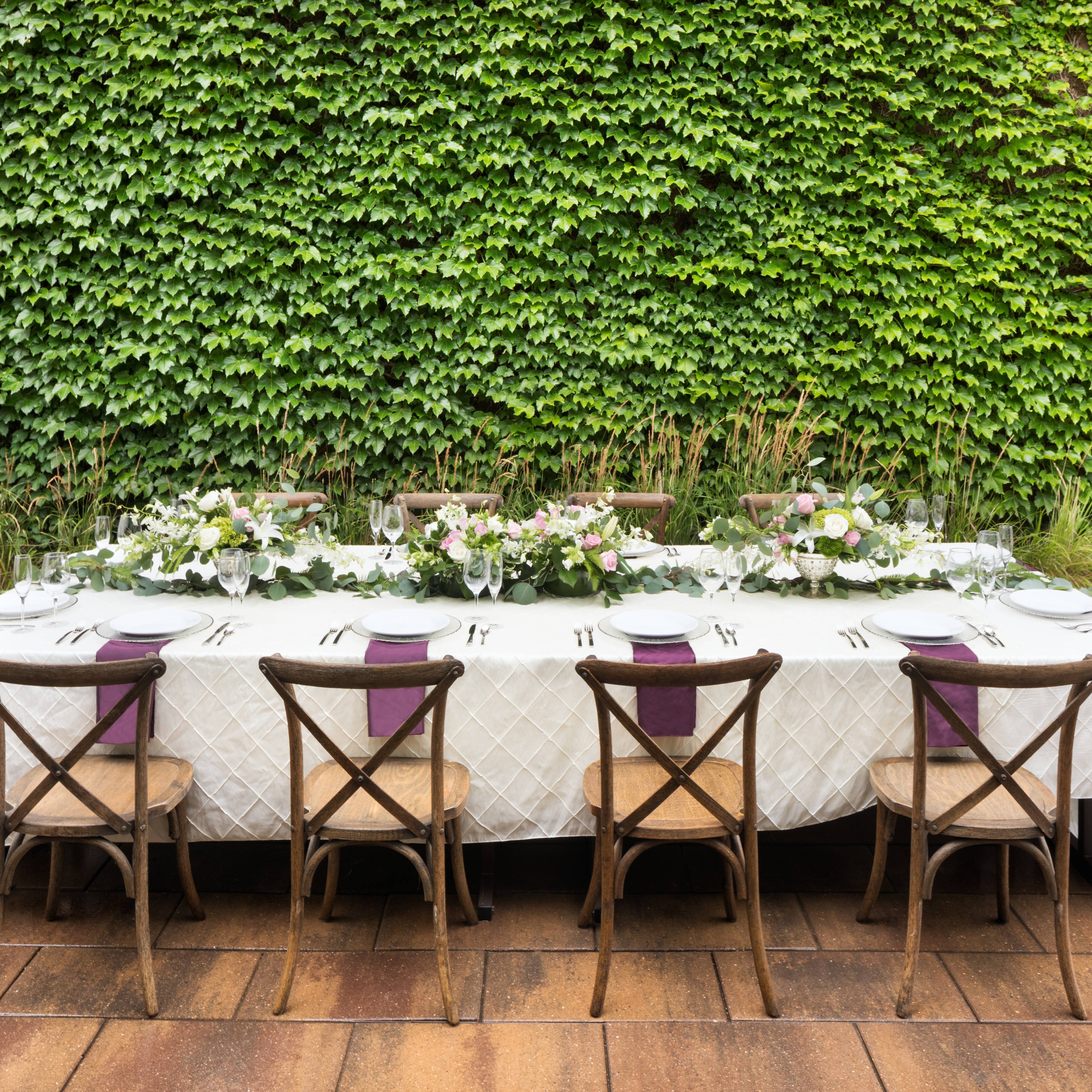 Wedding reception table beside a wall of ivy