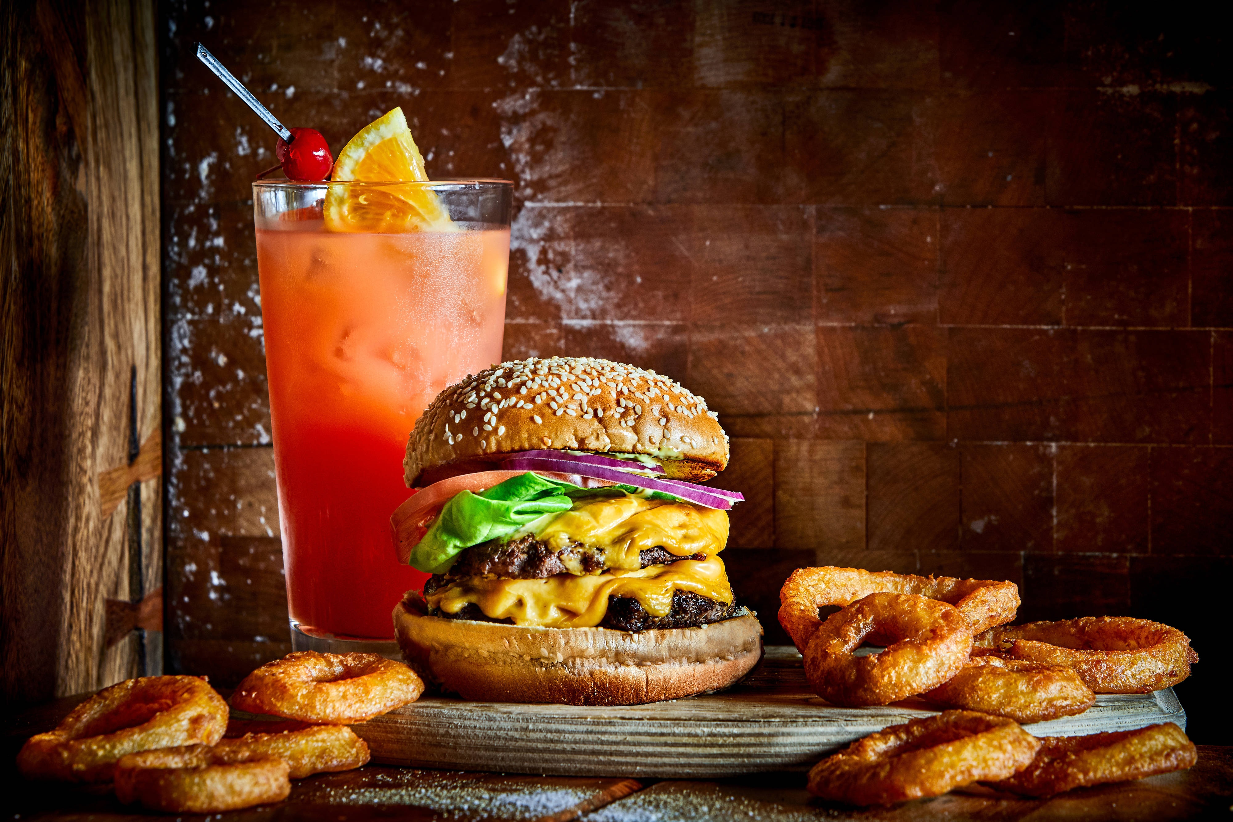 Double cheeseburger with onion rings and a cocktail