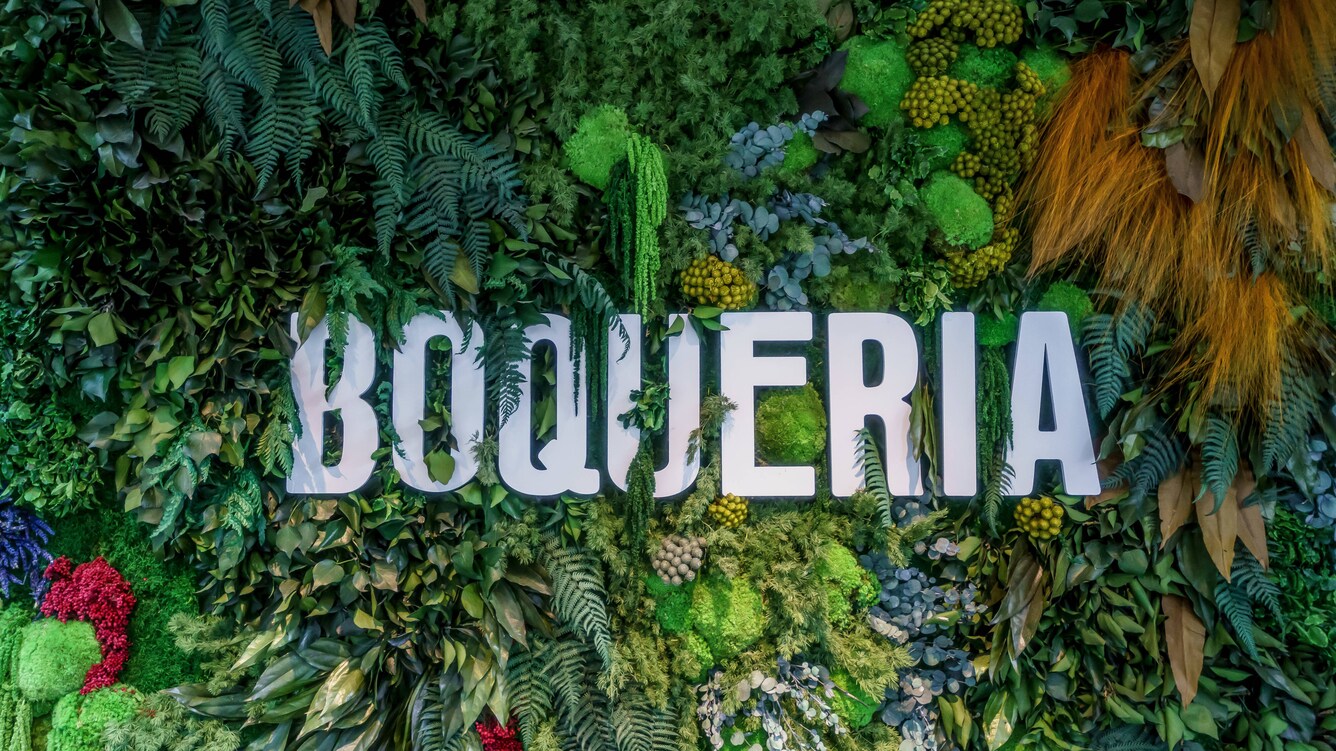 Boqueria sign amidst lush, tropical plants on a wall.