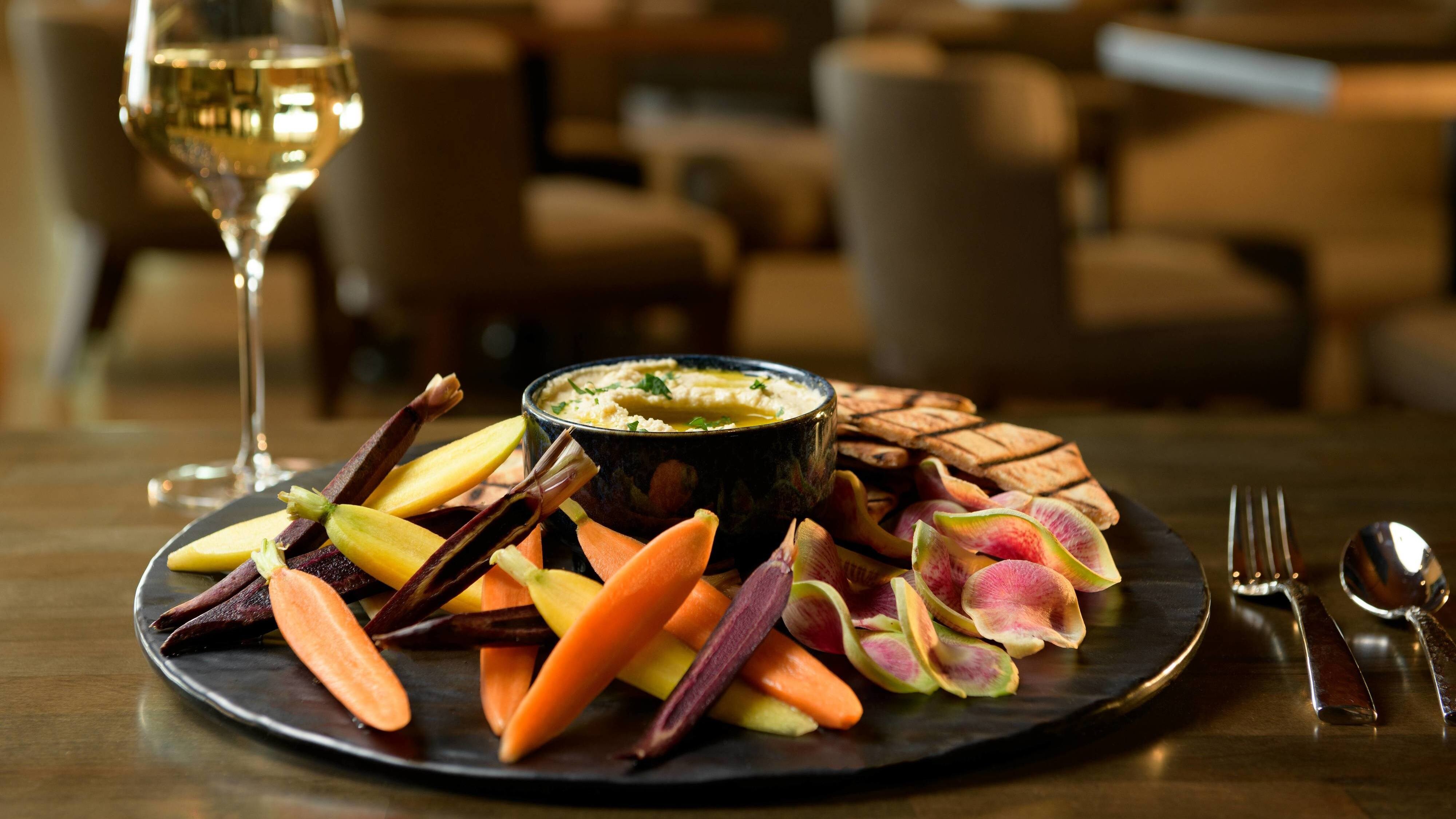 A tray of appetizers and a glass of wine