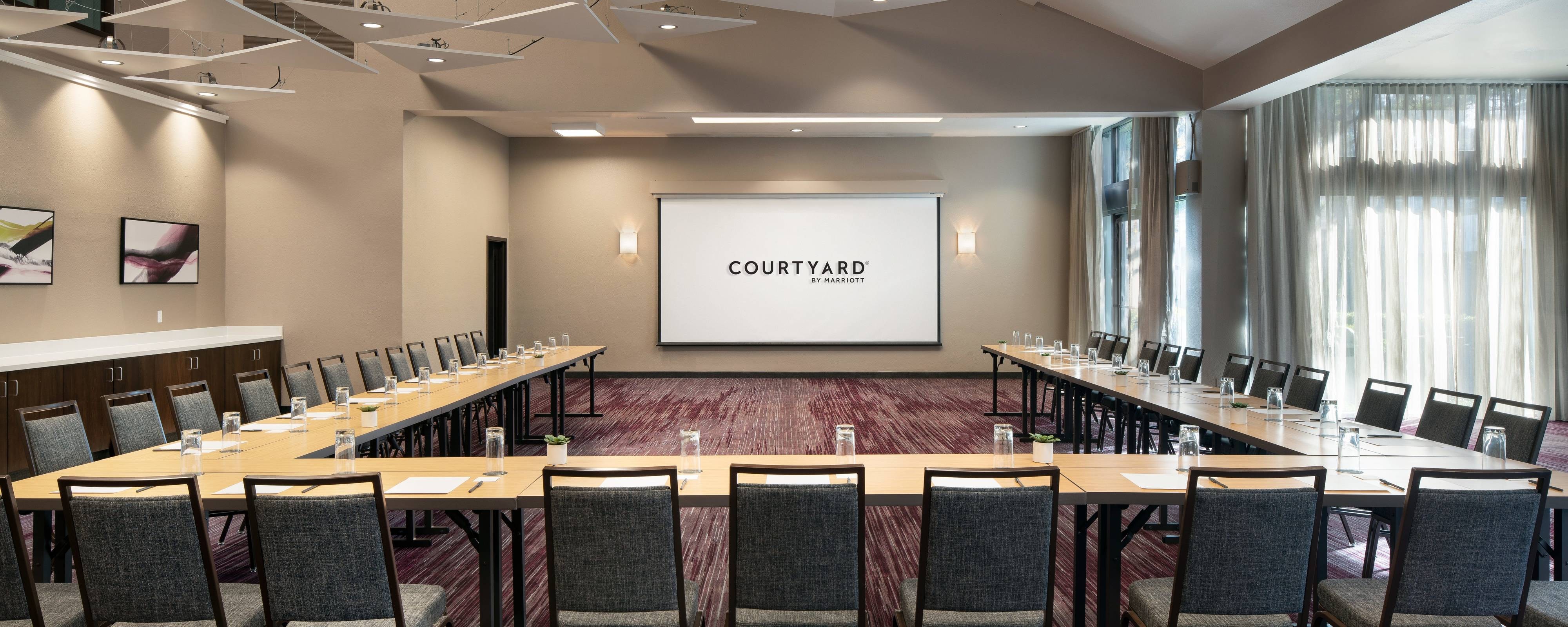 Meeting room with U-shape table setup and projector screen