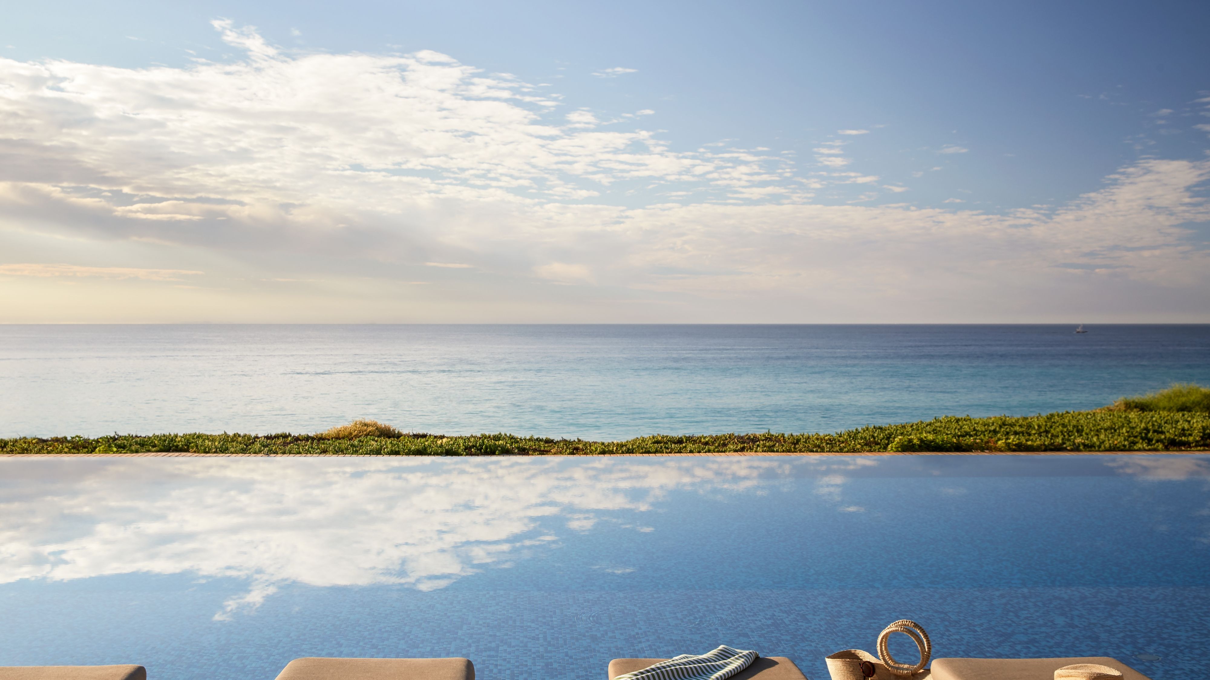 Lounge chairs at infinity's pool edge overlooking ocean