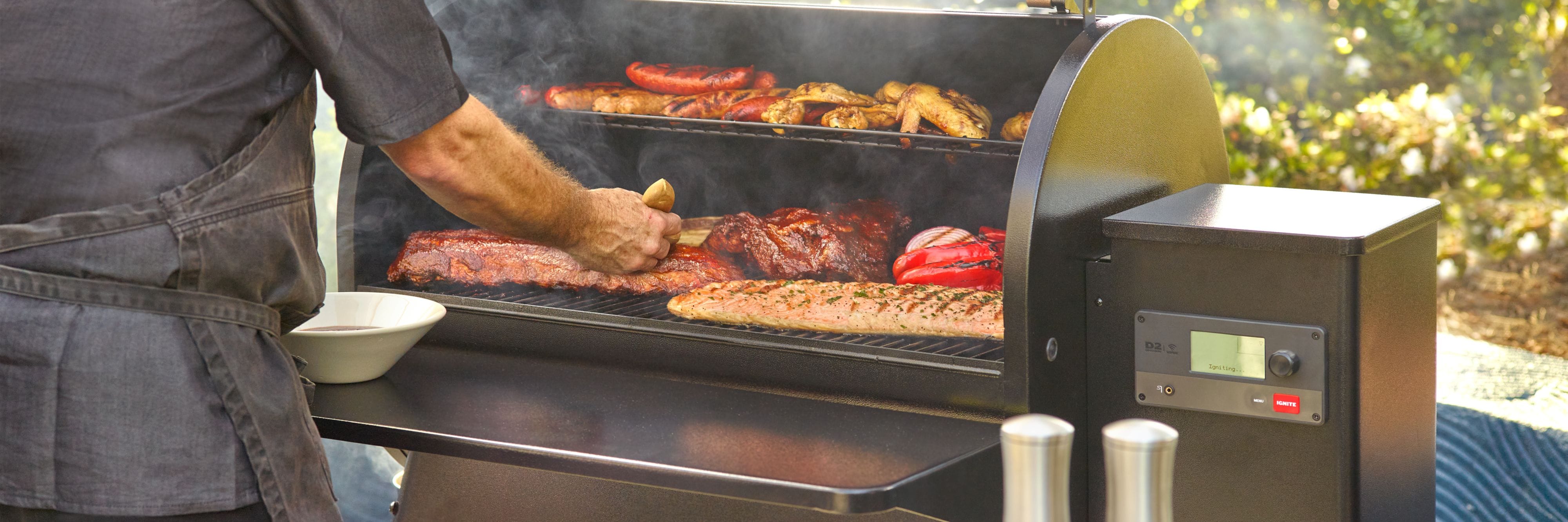 Person grilling various meats and vegetables