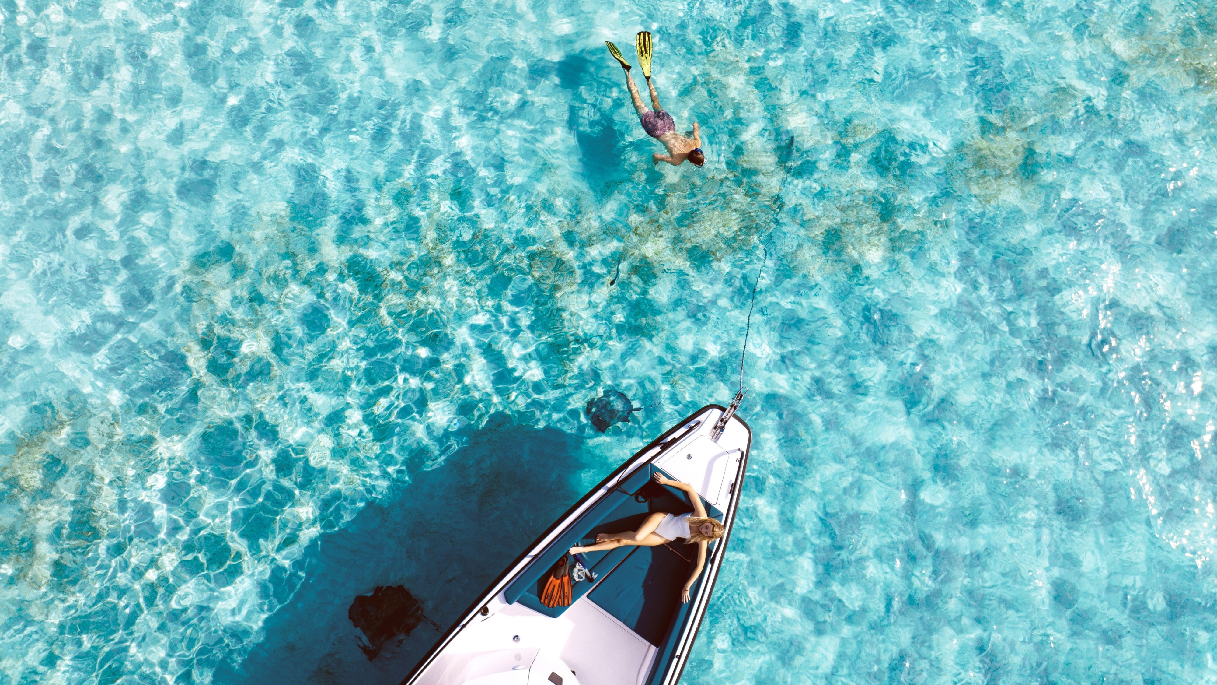 tt tempo traveller price Person snorkeling next to a boat with a person sunbathing on deck