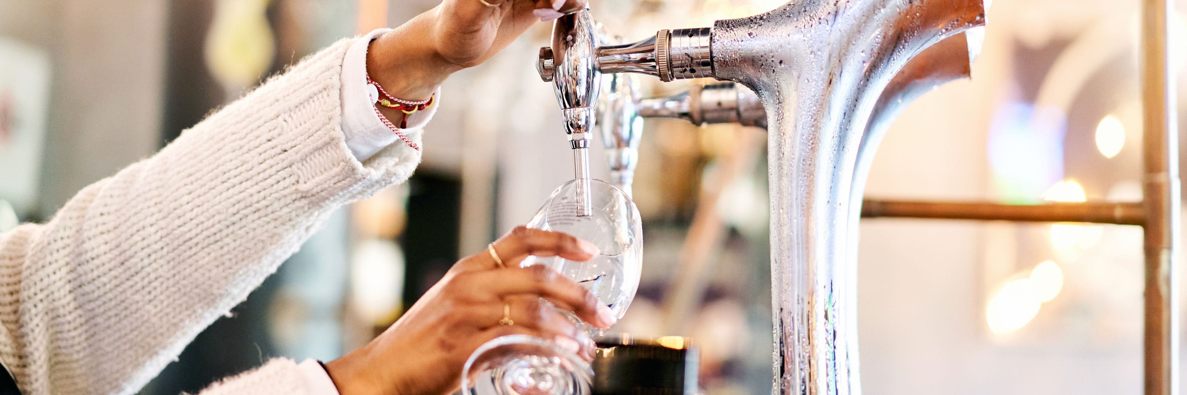 Person pouring a drink from a bar tap