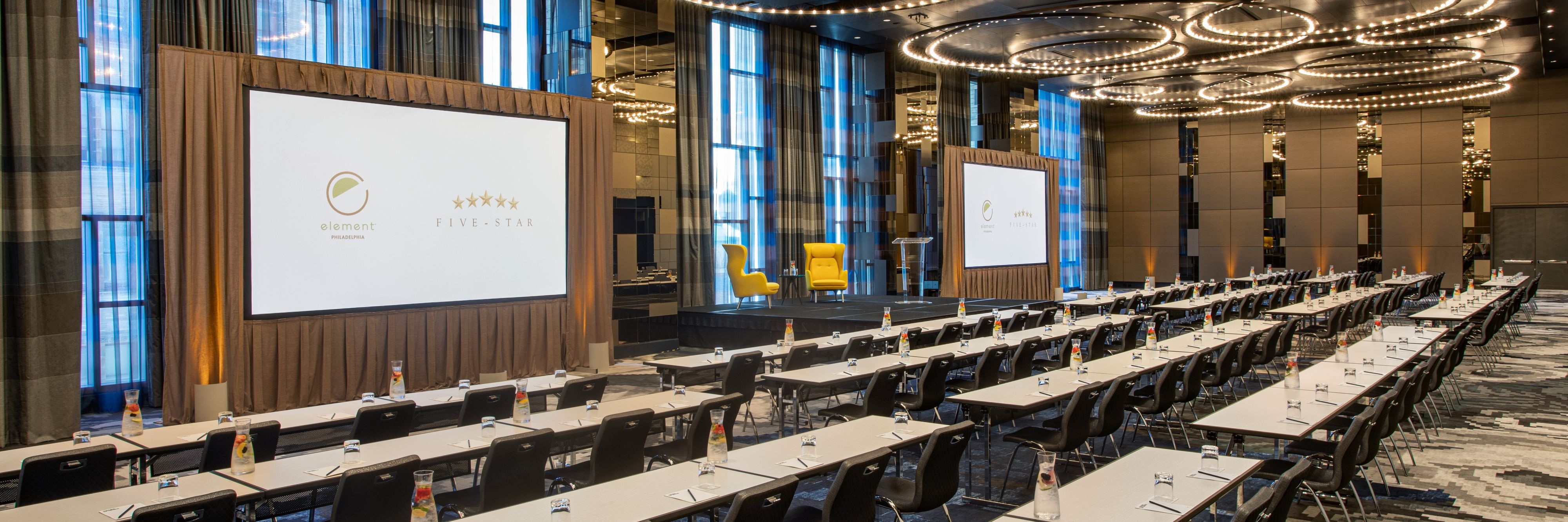 Meeting room setup in ballroom with stage and projector screens