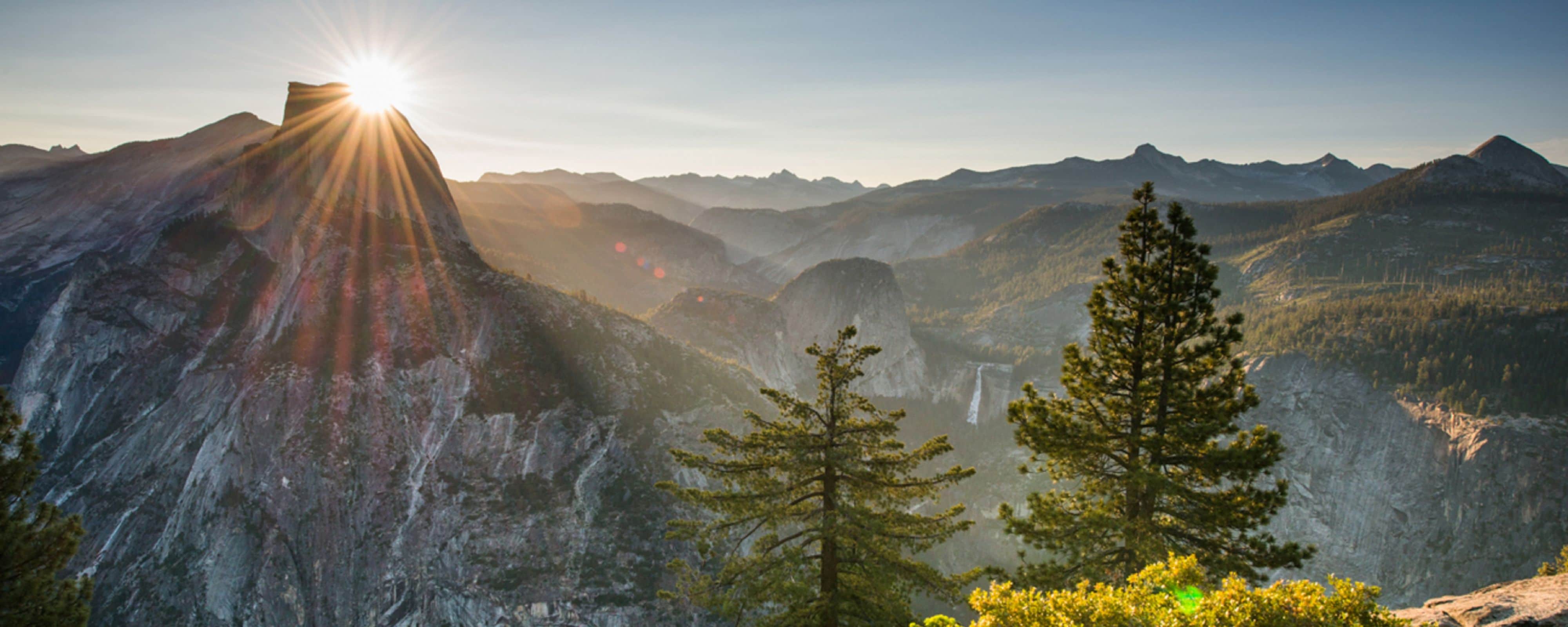 The sun over a forested mountain