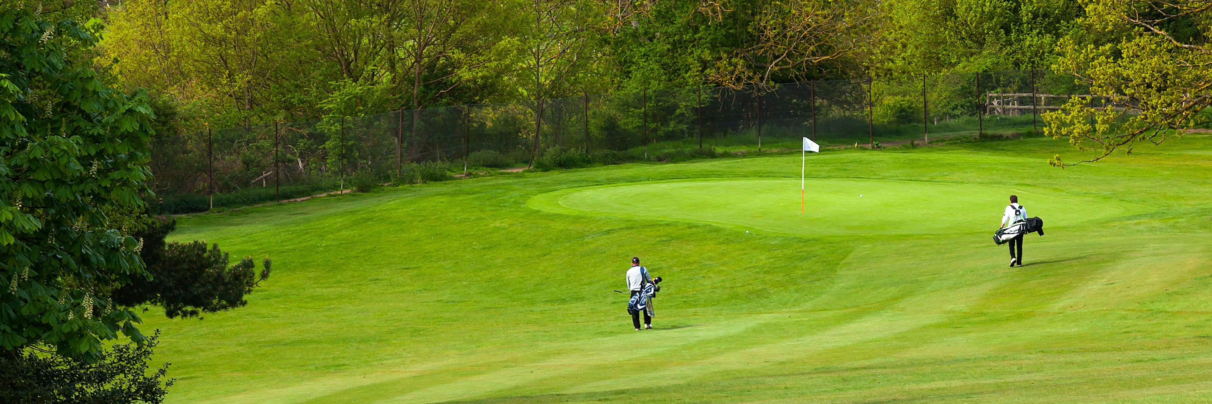 People carrying golf club bags on a course