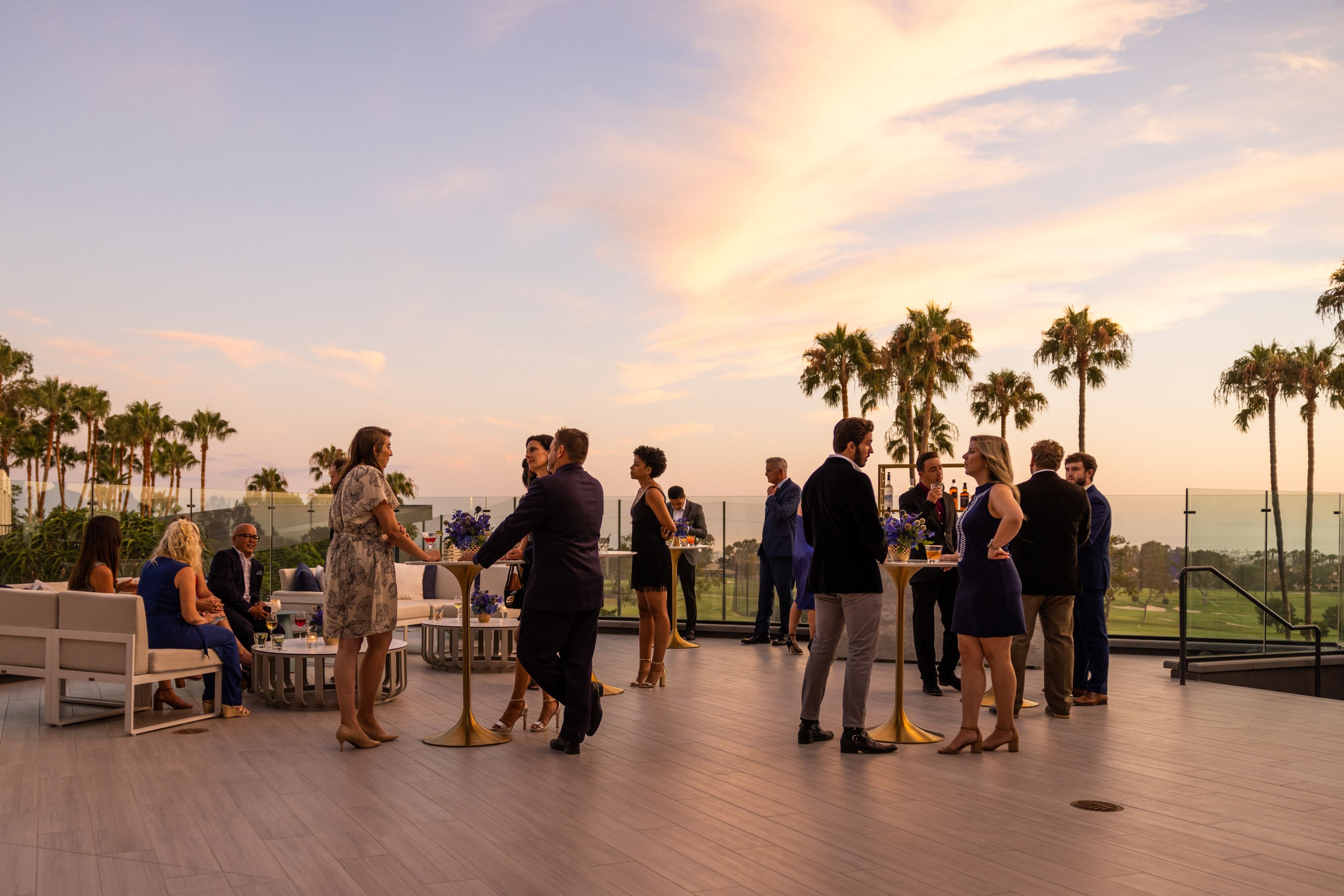 People socializing at an event on an outdoor terrace at dusk