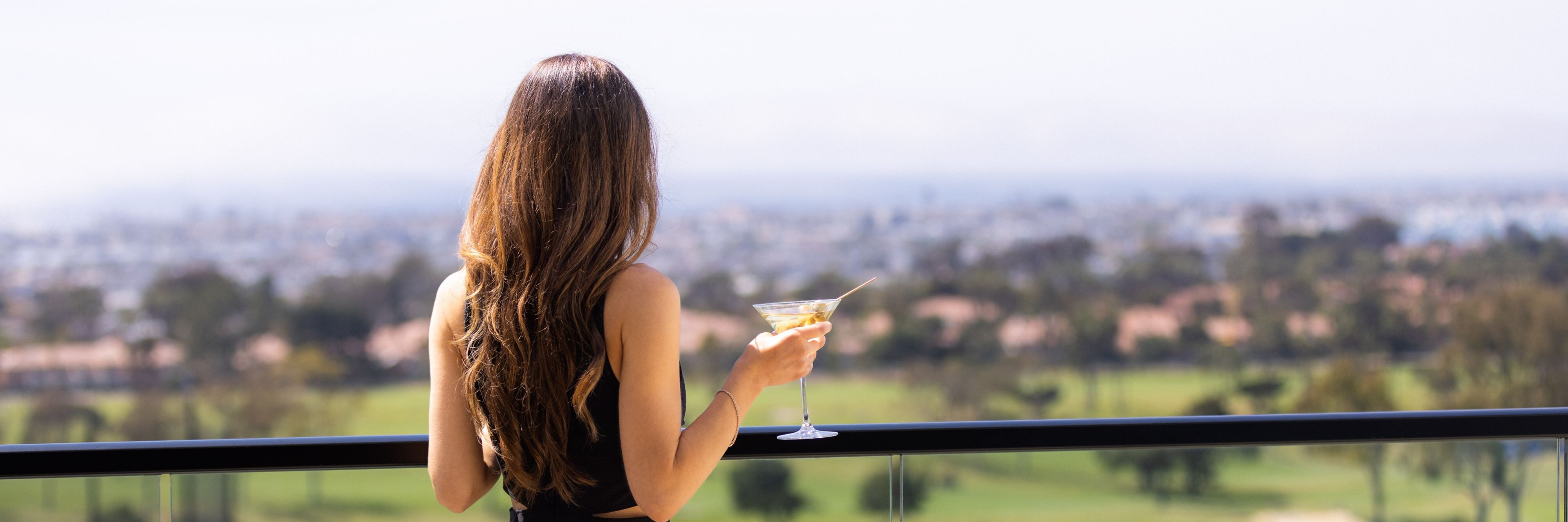 Person standing on hotel balcony holding a drink