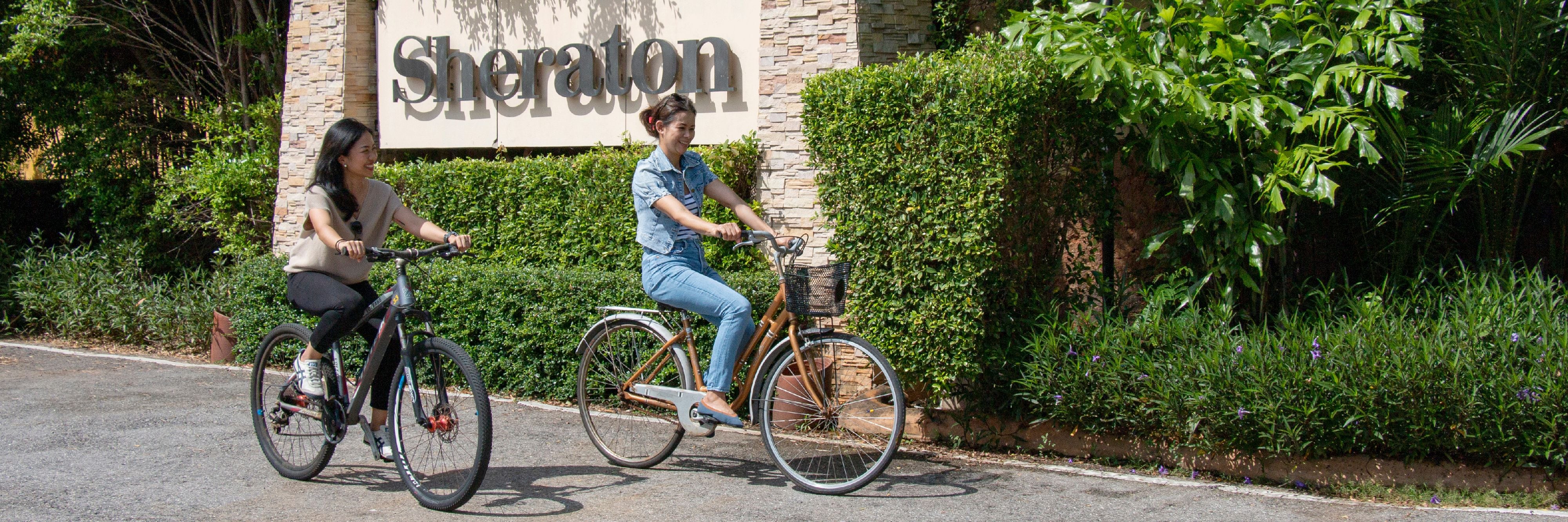 People bicycling beside the Sheraton sign