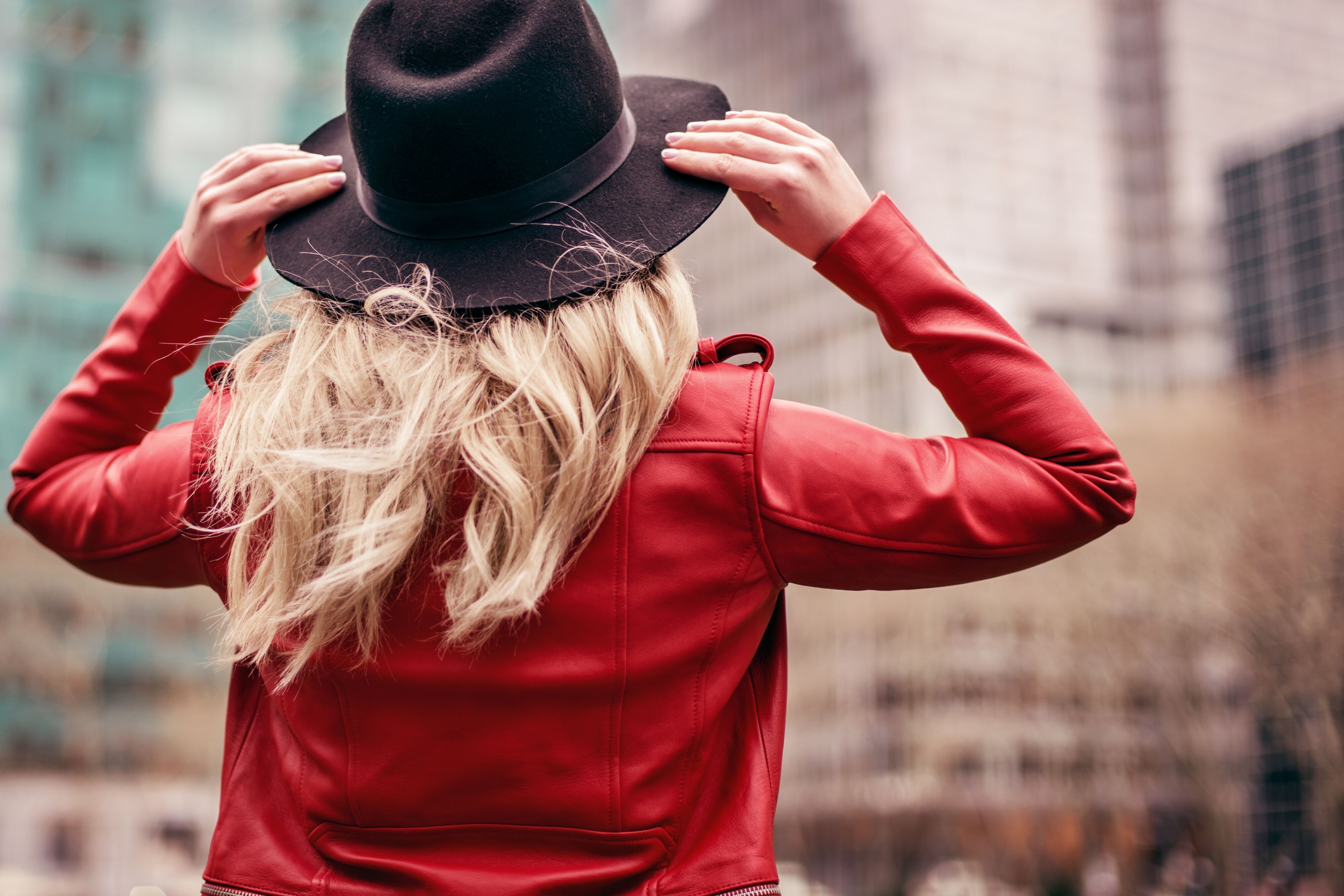 Woman holding onto her hat and looking at buildings